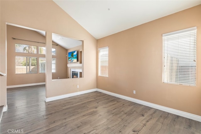 unfurnished living room with a tile fireplace, vaulted ceiling, and dark hardwood / wood-style flooring