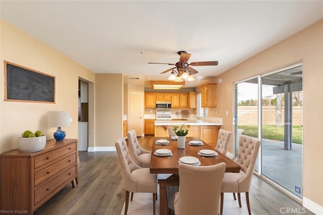 dining space with ceiling fan and dark hardwood / wood-style flooring