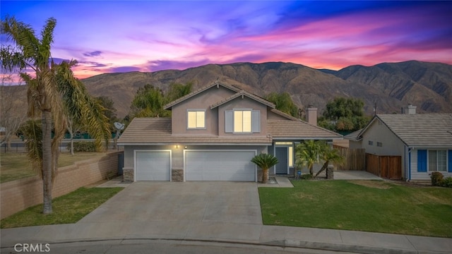 view of front of property with a garage, a mountain view, and a lawn