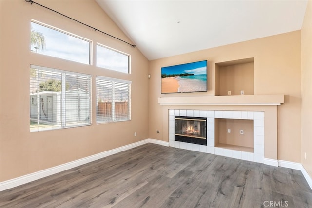 unfurnished living room with a tiled fireplace, hardwood / wood-style floors, and high vaulted ceiling