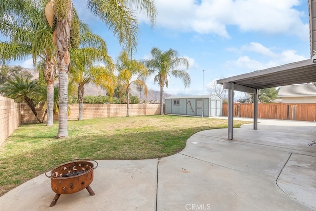 view of yard featuring a storage shed, an outdoor fire pit, and a patio