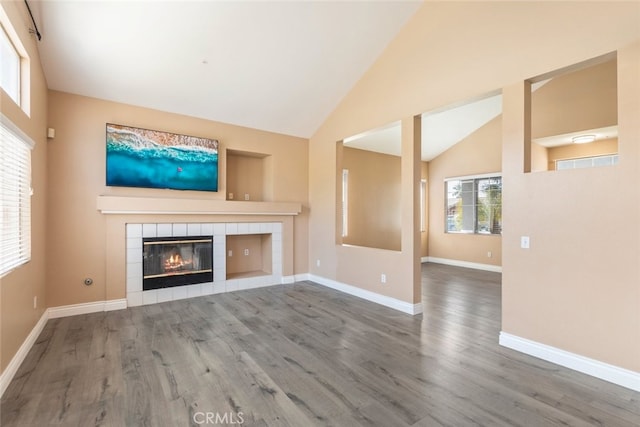 unfurnished living room featuring hardwood / wood-style floors, a fireplace, and high vaulted ceiling