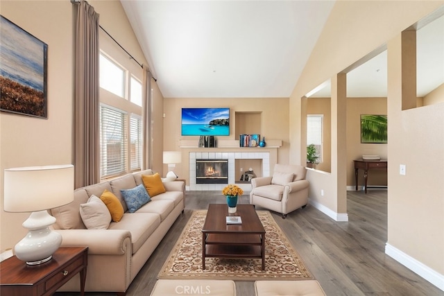 living room with a tile fireplace, hardwood / wood-style floors, and high vaulted ceiling