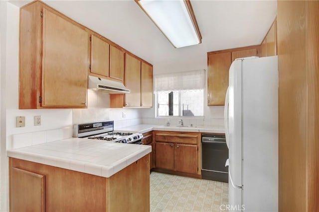 kitchen with sink, tile countertops, white appliances, and kitchen peninsula