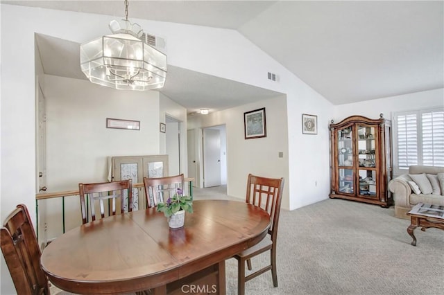 carpeted dining area featuring a notable chandelier and vaulted ceiling