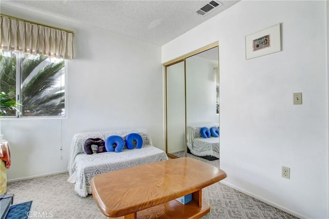 bedroom with light carpet, a textured ceiling, and a closet