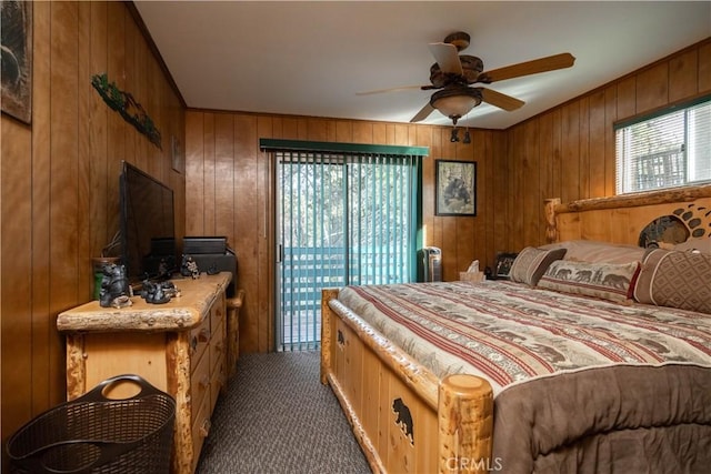 bedroom with dark carpet, access to outside, wooden walls, and ceiling fan