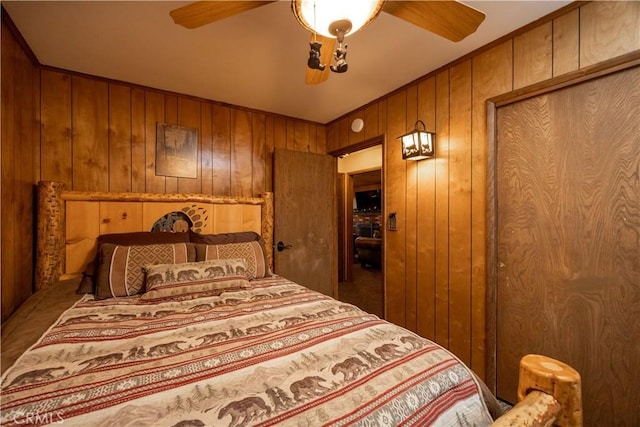 bedroom with ceiling fan and wooden walls