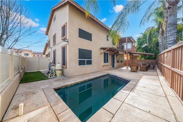 rear view of property with an outdoor living space, a fenced in pool, and a patio area