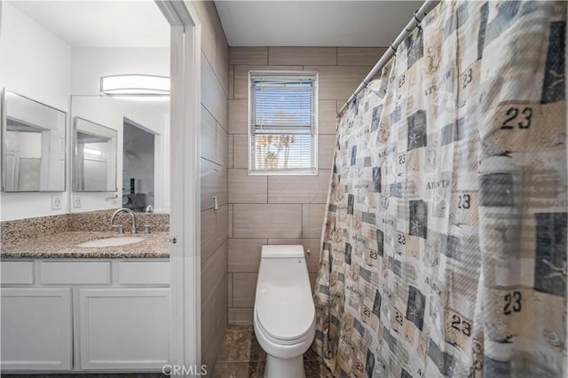 bathroom with a shower with curtain, vanity, toilet, and tile walls