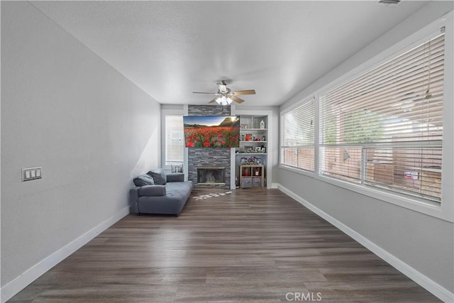 unfurnished room with ceiling fan, dark hardwood / wood-style floors, a fireplace, and built in shelves