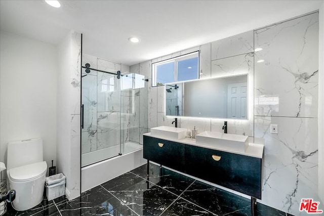 full bathroom featuring tile walls, vanity, enclosed tub / shower combo, and toilet