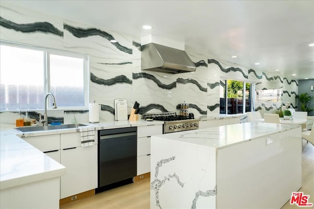 kitchen featuring black dishwasher, sink, white cabinets, wall chimney exhaust hood, and light hardwood / wood-style flooring