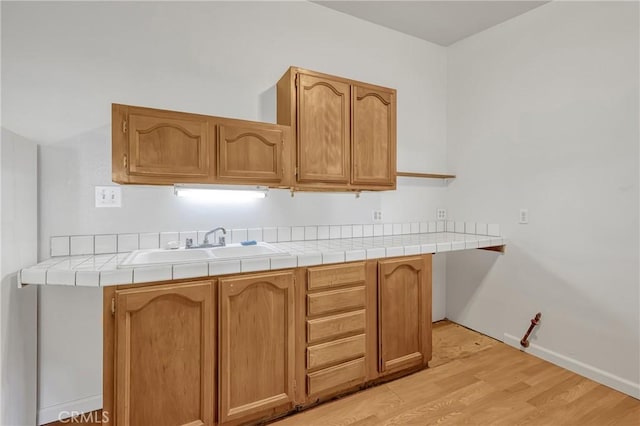 kitchen featuring sink, tile counters, and light hardwood / wood-style floors