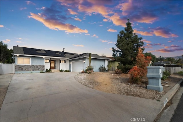 ranch-style house featuring a garage and solar panels