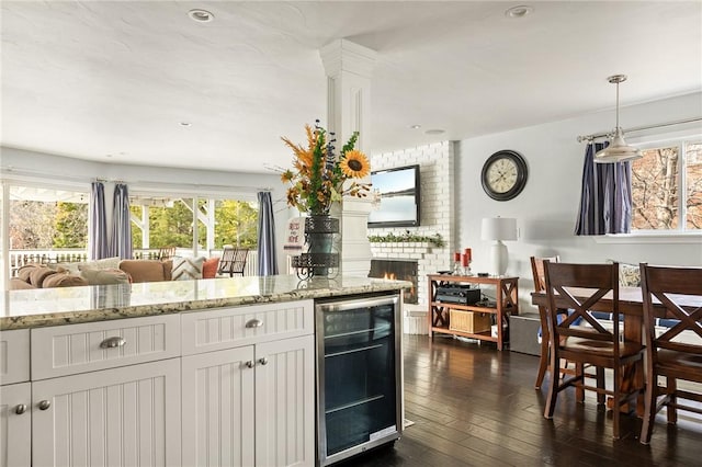 kitchen with wine cooler, dark hardwood / wood-style flooring, a fireplace, and white cabinets