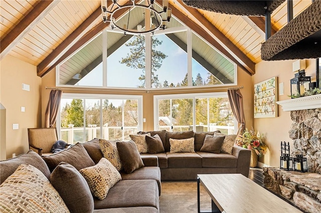 living room with beamed ceiling, a stone fireplace, and high vaulted ceiling