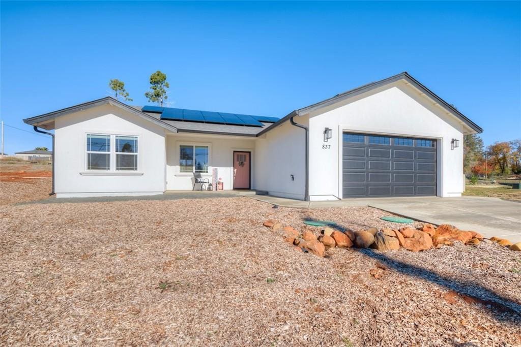 ranch-style house featuring a garage and solar panels