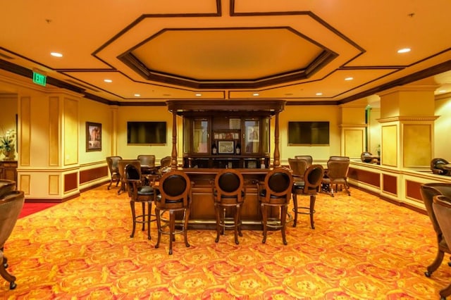 interior space featuring bar, ornamental molding, light colored carpet, and a tray ceiling