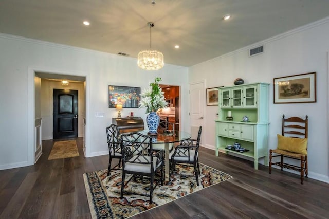 dining room with crown molding, dark wood-type flooring, and a chandelier