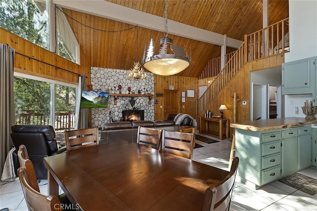 tiled dining space featuring a stone fireplace, high vaulted ceiling, wood walls, beamed ceiling, and wood ceiling