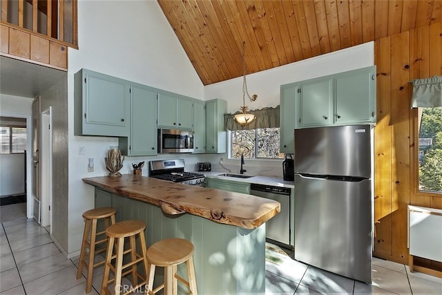 kitchen featuring sink, a breakfast bar, appliances with stainless steel finishes, butcher block counters, and kitchen peninsula