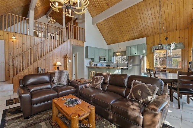 living room featuring tile patterned flooring, high vaulted ceiling, beamed ceiling, a chandelier, and wood walls