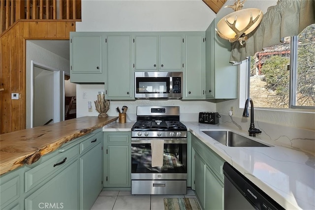 kitchen featuring appliances with stainless steel finishes, sink, light tile patterned floors, and green cabinetry