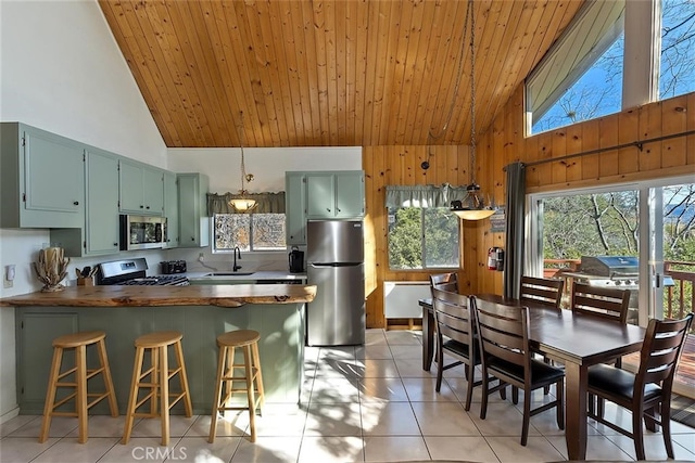 kitchen featuring appliances with stainless steel finishes, a breakfast bar, sink, wooden counters, and kitchen peninsula