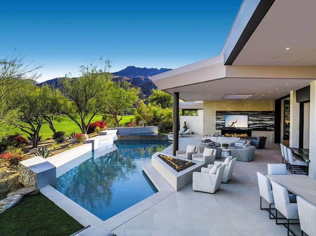 view of swimming pool with an outdoor fire pit, a mountain view, and a patio area