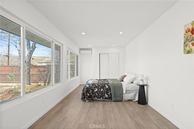 bedroom with multiple windows, light wood-type flooring, and a closet