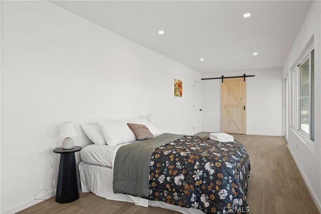 bedroom featuring wood-type flooring and a barn door