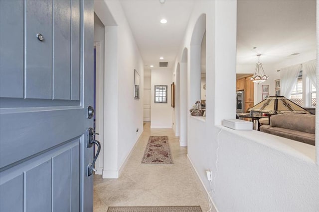 hall with light tile patterned floors and a healthy amount of sunlight