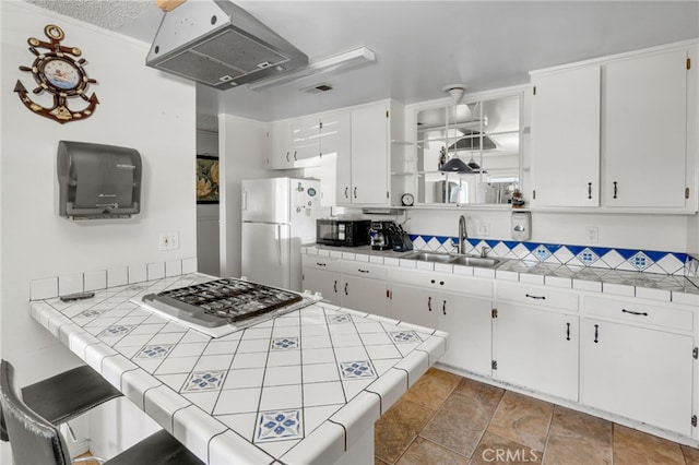 kitchen featuring sink, white cabinetry, white refrigerator, ventilation hood, and tile countertops