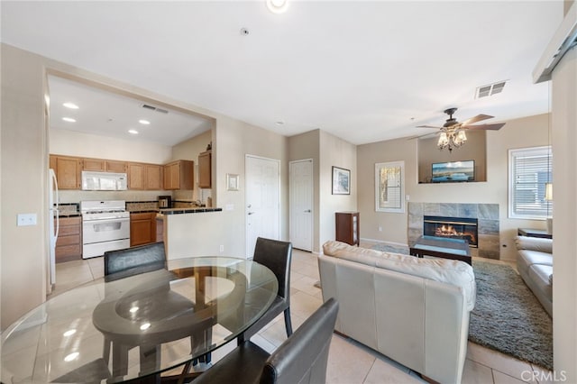 tiled dining area featuring ceiling fan and a premium fireplace