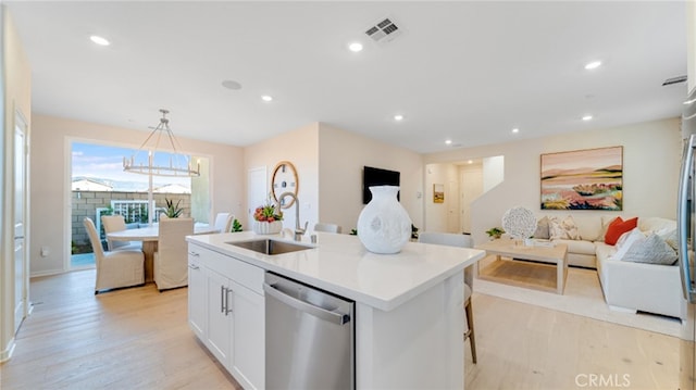 kitchen featuring decorative light fixtures, white cabinetry, sink, a kitchen island with sink, and stainless steel dishwasher