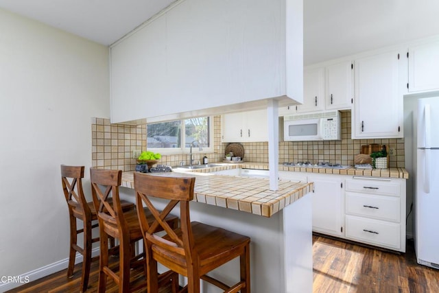 kitchen featuring sink, tile countertops, white cabinets, and white appliances