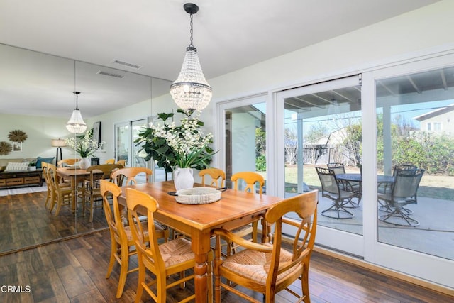 dining space featuring dark wood-type flooring and a notable chandelier