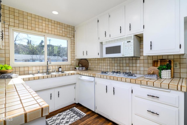 kitchen with sink, white appliances, tile counters, and white cabinets