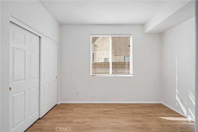 unfurnished bedroom with light hardwood / wood-style flooring and a closet