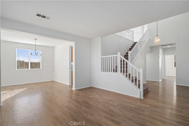 unfurnished living room featuring an inviting chandelier and dark hardwood / wood-style flooring