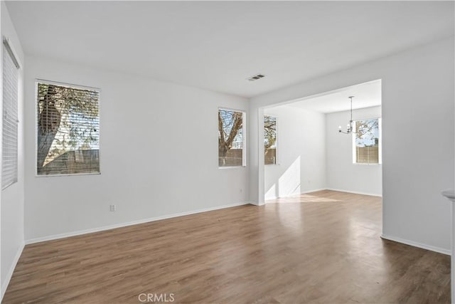 spare room featuring hardwood / wood-style flooring and a chandelier