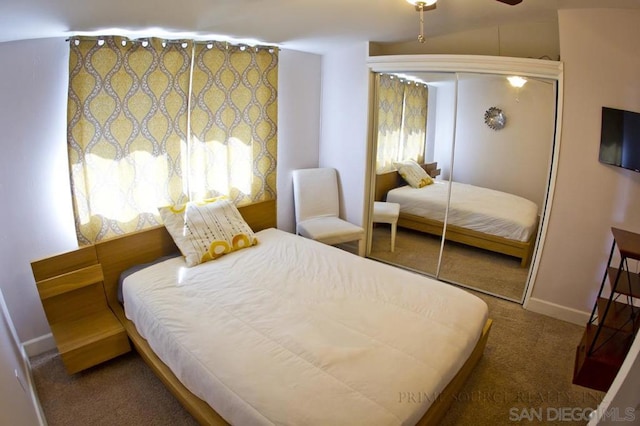 bedroom with vaulted ceiling, multiple windows, ceiling fan, dark carpet, and a closet