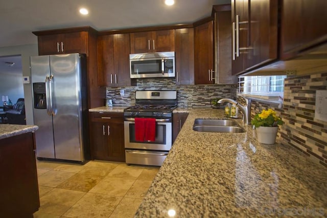 kitchen featuring light stone counters, appliances with stainless steel finishes, sink, and decorative backsplash