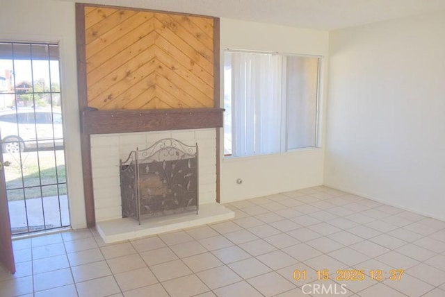 unfurnished living room with a brick fireplace and light tile patterned floors