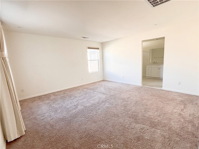 spare room with carpet flooring, baseboards, and visible vents