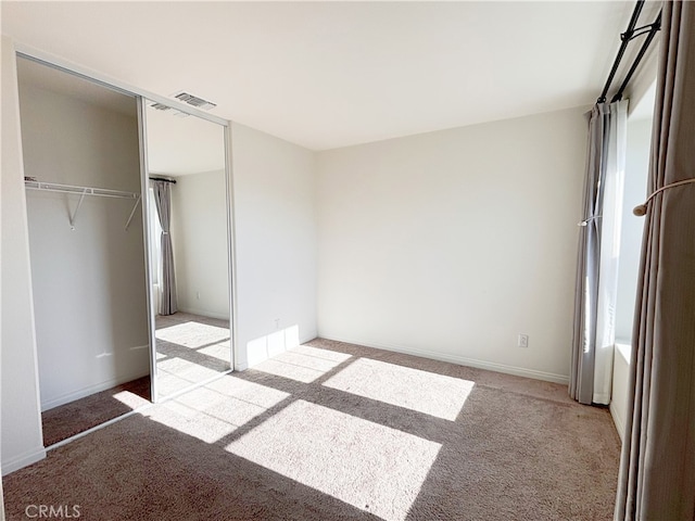 unfurnished bedroom featuring light carpet, visible vents, and a closet