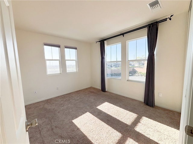 unfurnished room with carpet flooring, a healthy amount of sunlight, visible vents, and baseboards