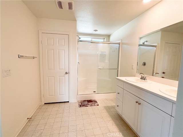 full bath with baseboards, visible vents, double vanity, a stall shower, and a sink