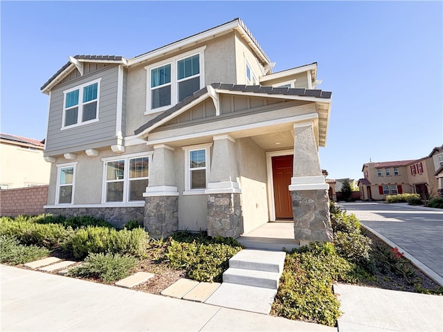 craftsman inspired home featuring stone siding, stucco siding, and board and batten siding